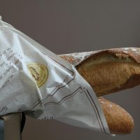 Crisp and golden French baguette wrapped in elegant paper packaging from a bakery.